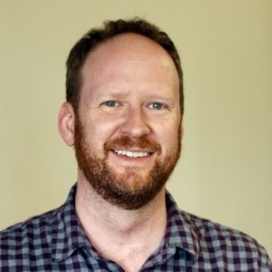 headshot of Scott Downes, in a flannel shirt, from LinkedIn